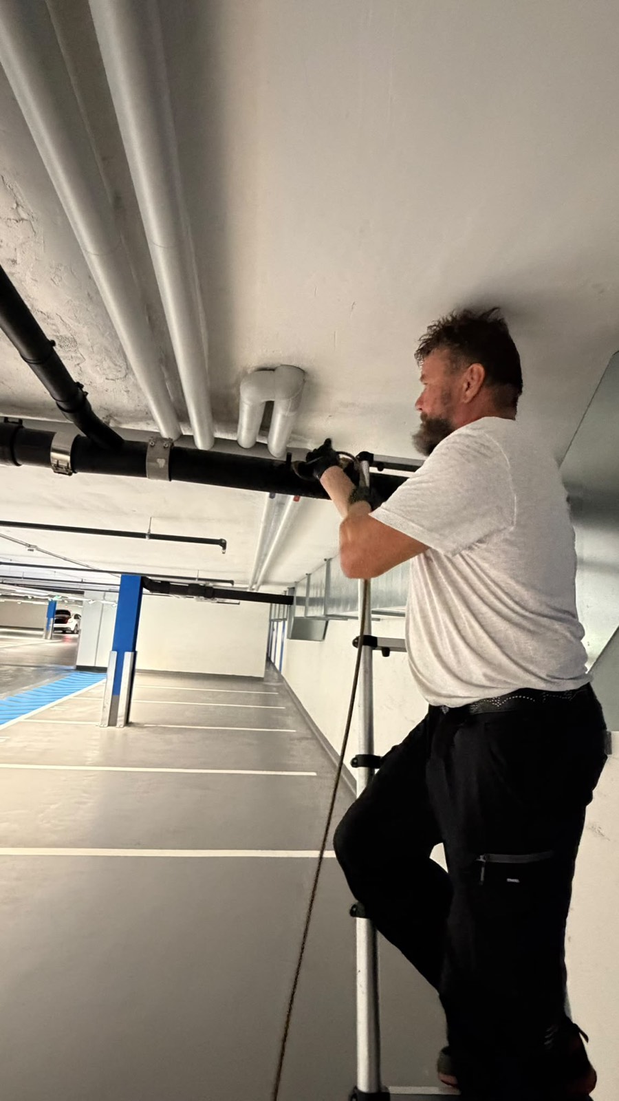 Rohrreinigung an einer Deckenleitung in einer Tiefgarage