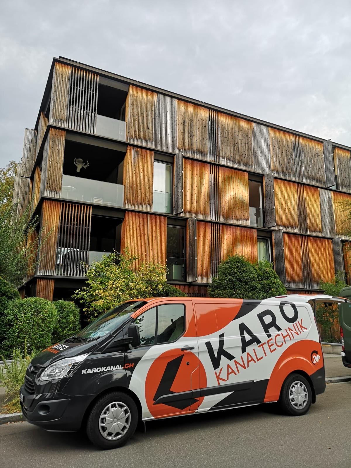 Einsatzfahrzeug vor einem modernen Wohnhaus mit Holzfassade