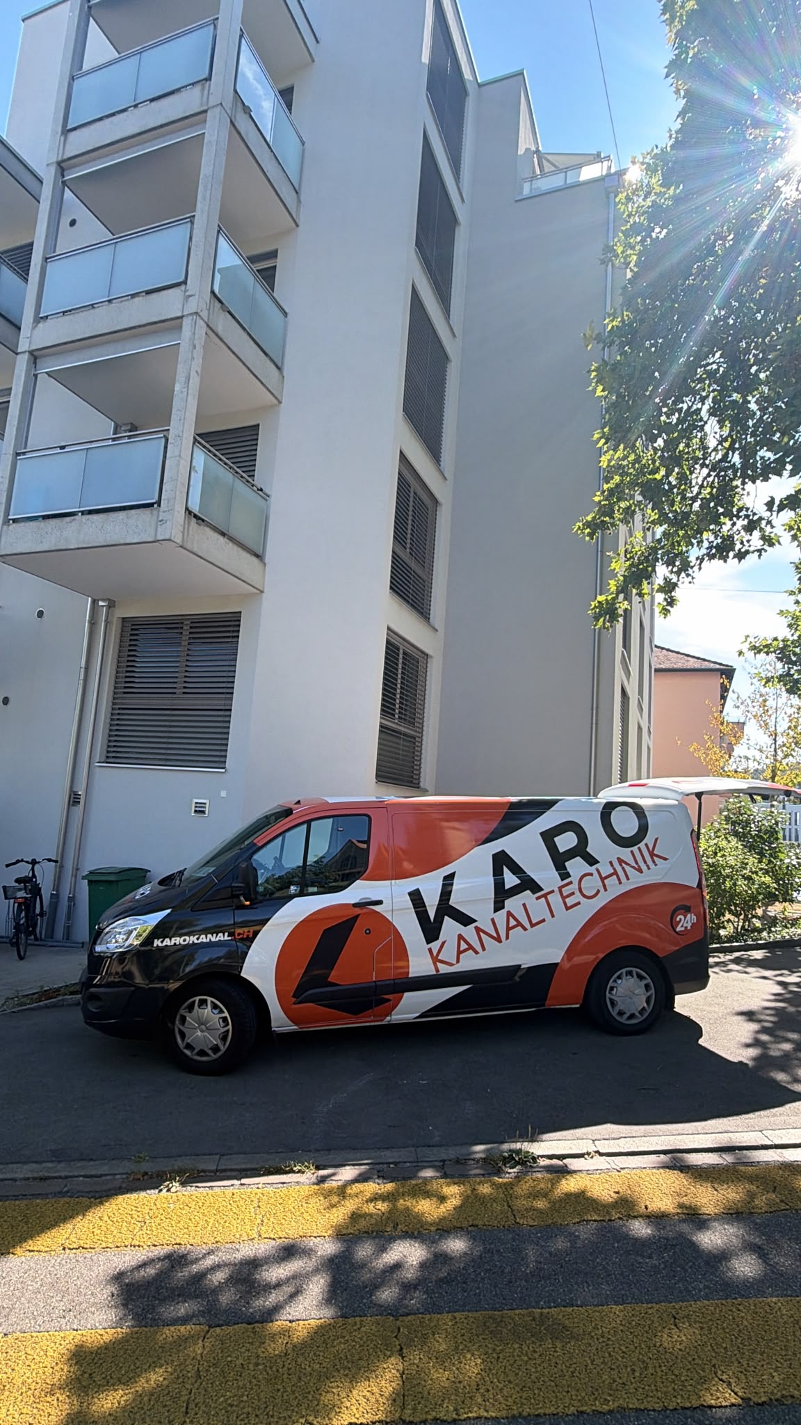 Einsatzfahrzeug von Karo Kanaltechnik vor einem Wohnhaus an einem Sommertag