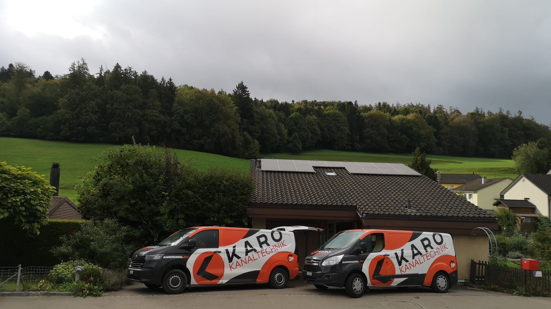 Zwei Karo-Einsatzfahrzeuge vor einem Einfamilienhaus – Kanalreinigung im Team