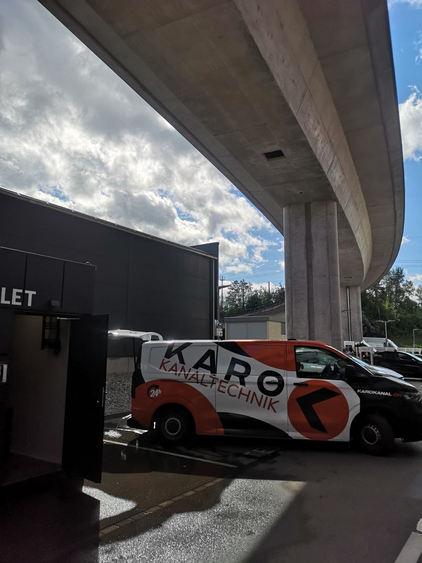 Karo-Einsatzfahrzeug bei Reinigungsarbeiten an einer Raststätte unter einem Autobahnviadukt